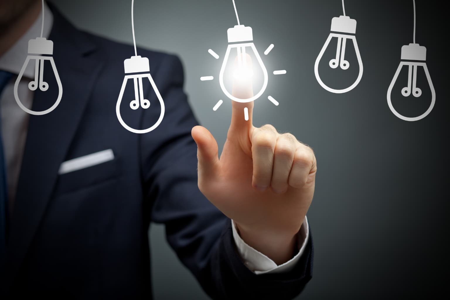 Hombre de negocios tocando una bombilla encendida entre varias apagadas, representando la elección de una idea de emprendimiento innovadora