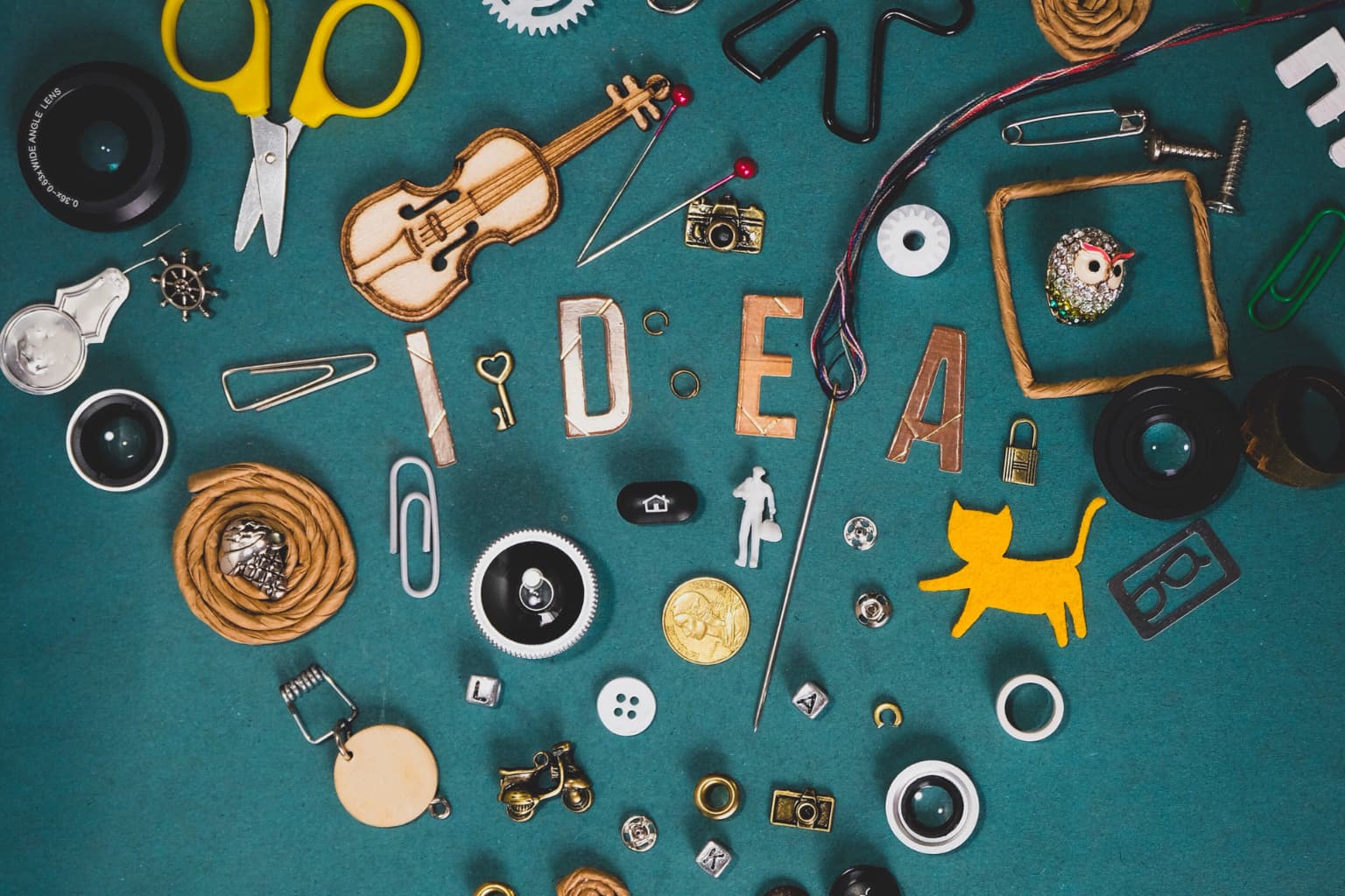 Composición creativa con objetos variados sobre fondo verde que forman la palabra “IDEA”, representando el proceso de generación de ideas de emprendimiento
