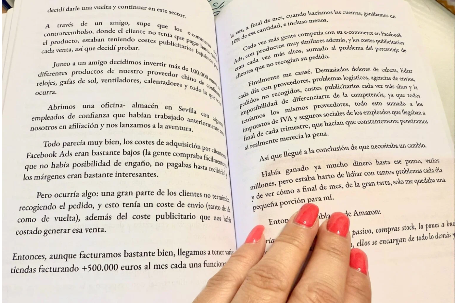 Fotografía de un libro abierto sostenido por una mano con uñas pintadas de color coral. El texto del libro está en español y narra la experiencia de un emprendedor que invierte 100.000 euros en un e-commerce con productos de un proveedor chino. Habla sobre abrir una oficina en Sevilla, los costos bajos de adquisición con Facebook Ads y los problemas que surgieron cuando muchos clientes no recogían sus pedidos. A pesar de facturar más de 500.000 euros al mes, los márgenes eran reducidos y el narrador concluye que necesitaba un cambio, cansado de los problemas logísticos y financieros del negocio.
